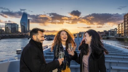 Friends enjoy champagne as the sunsets over the River Thames in London