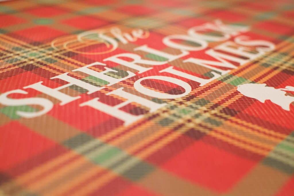 The red cover of a Sherlock Holmes book is pictured with white font. 