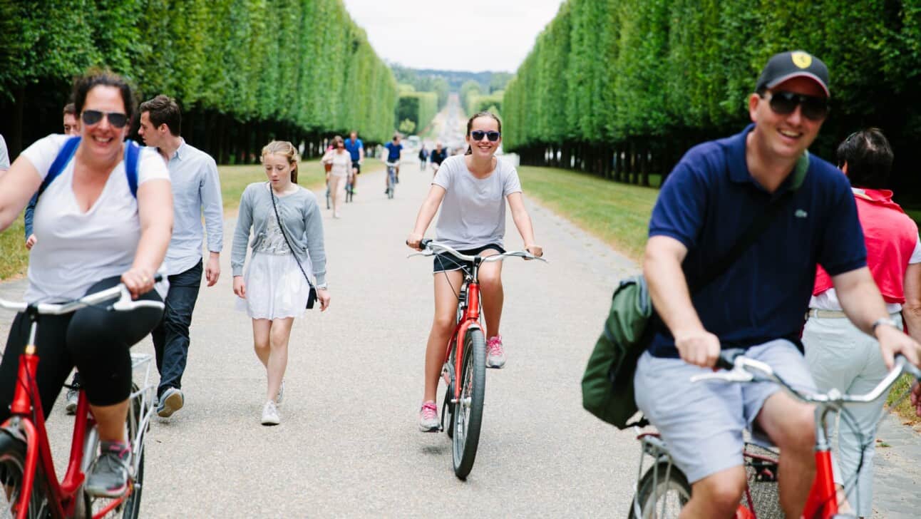 A family rides their bikes through the gardens in Versailles